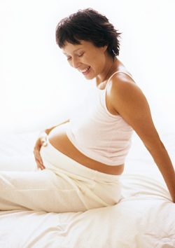 Pregnant woman with hand on stomach, smiling